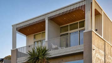 A modern two-story building with a balcony, large windows, and a wooden ceiling.