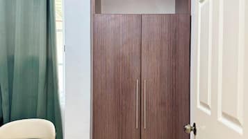 Ein Zimmer mit Schrank, Stuhl und Vorhang.