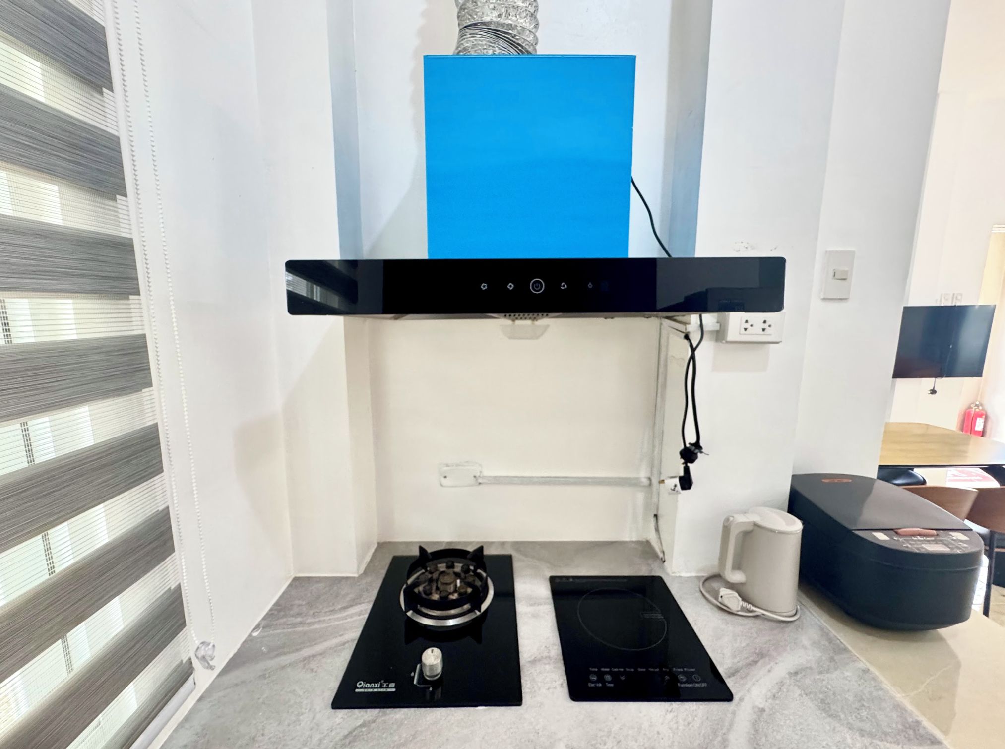 Eine moderne Küche mit Gasherd, Induktionskochfeld und einer blauen Dunstabzugshaube.