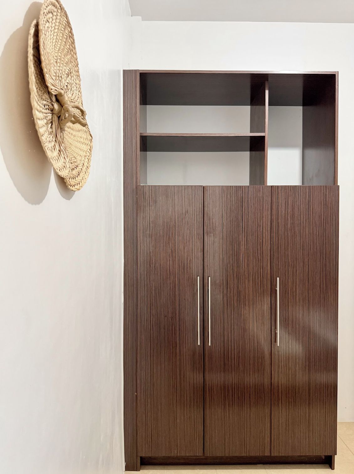Ein dunkler Holzkleiderschrank mit zwei Schubladen und einer Glastür.