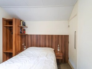 Ein Schlafzimmer mit einem Bett, einem Holzschrank und einem kleinen Regal mit Büchern.
