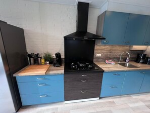 A modern kitchen with a black stove, blue cabinets, and a wooden countertop. - Characteristic group accommodation on a park (Stramproy)