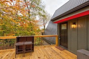 Eine Holzterrasse mit Metallgeländer, einer Bank und einer Tür mit rotem Akzent.