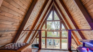 A wooden interior with a sloped ceiling, a chessboard, and a view of the outdoors. - LUXE | SKI-IN/OUT | Hot Tub | Fire Pit | A Frame (Beech Mountain)