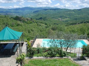 A pool with a view of mountains, a gazebo, and a stone patio. - Villa in Poppi With Swimming Pool (Poppi)