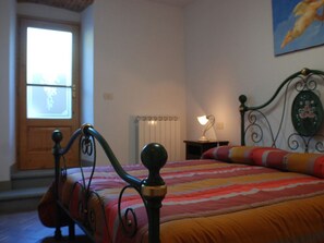 A bedroom with a bed, a window, a radiator, and a painting on the wall. - Villa in Poppi With Swimming Pool (Poppi)