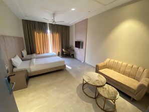 A hotel room with a bed, a sofa, a TV, and a ceiling fan. - Panchtala Resort (Mirzapur)