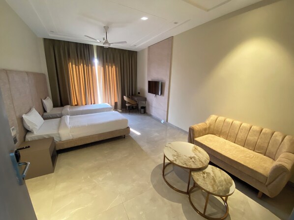 A hotel room with a bed, a sofa, a TV, and a ceiling fan.