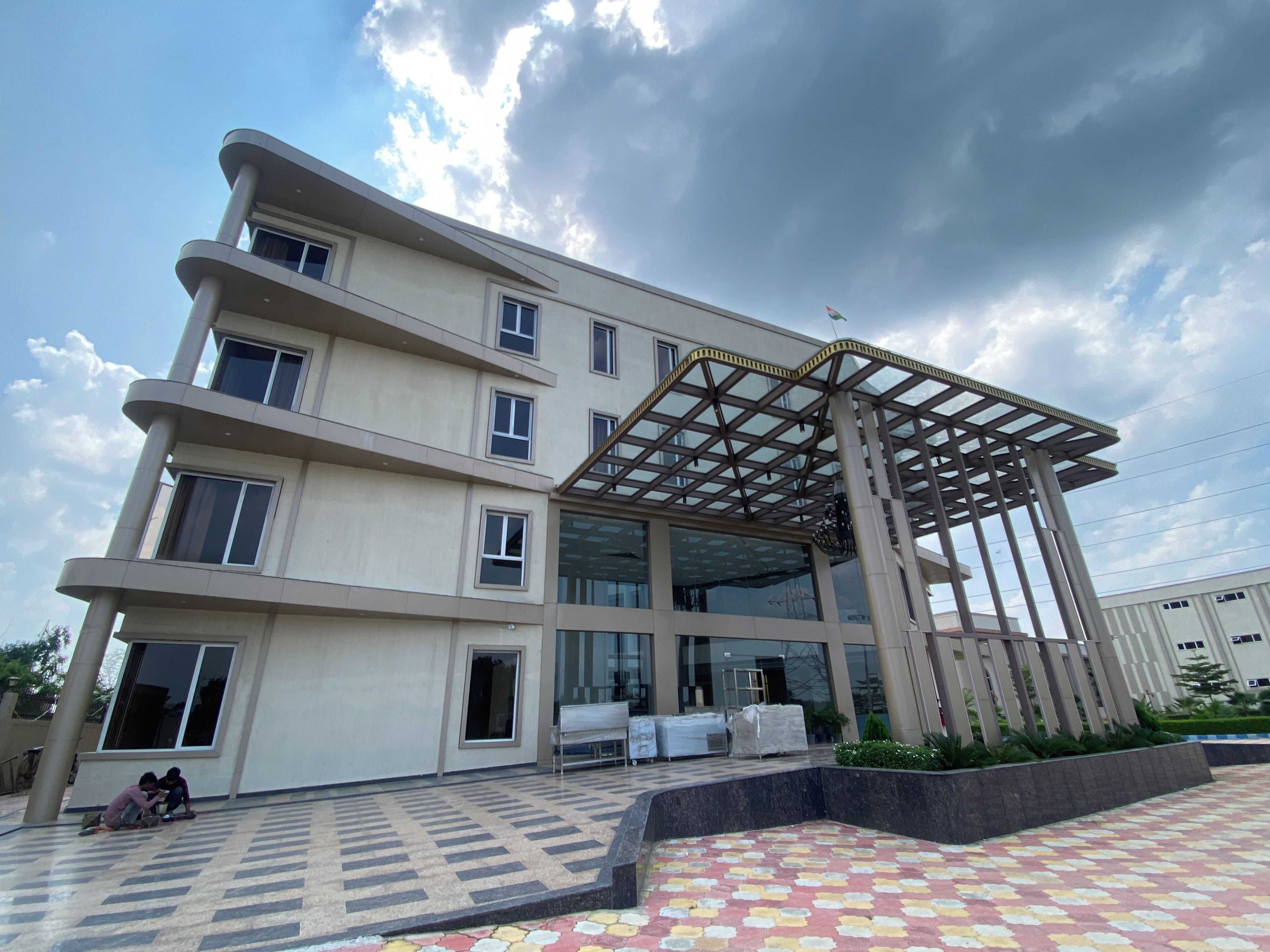Un edificio de varios pisos con un acceso cubierto y una plaza empavedada.