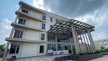 Un edificio de varios pisos con un acceso cubierto y una plaza empavedada.