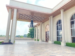 A building with a covered entrance, large columns, and a patterned floor.