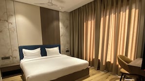 Ein Hotelzimmer mit einem großen Bett, einem Schreibtisch und einem Sessel.