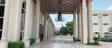 A building entrance with columns, a patterned floor, and a hanging chandelier.