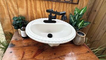 Un évier blanc avec un robinet noir, posé sur une table en bois.