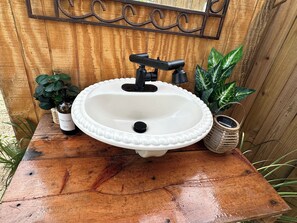 A white sink with a black faucet on a wooden table.