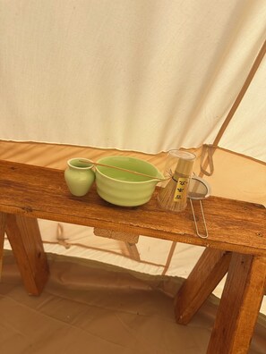 A wooden table with a green bowl, a green cup, and a strainer with Chinese characters.