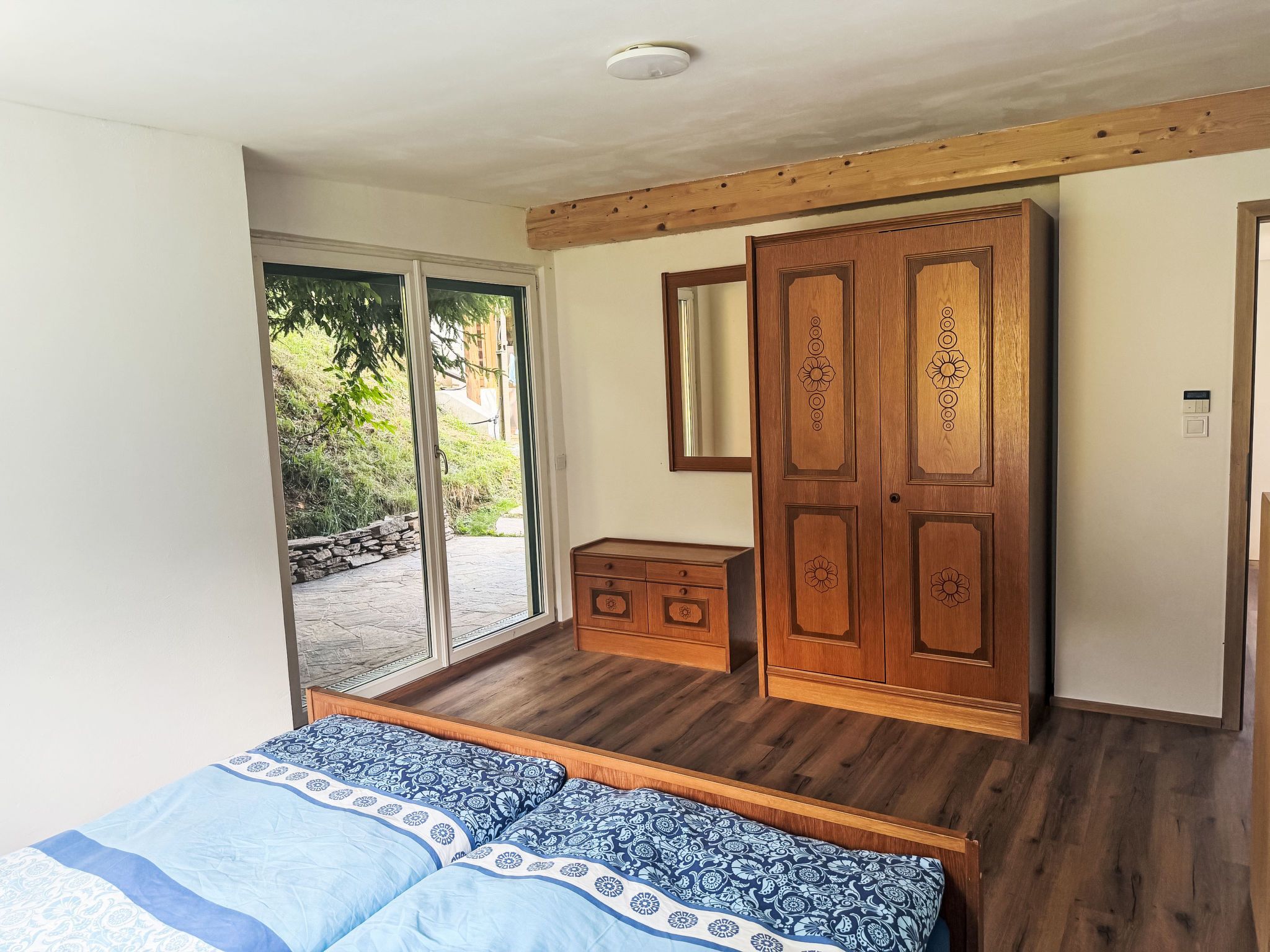 Ein Schlafzimmer mit einem Bett, einem Holzschrank und einem Spiegel.