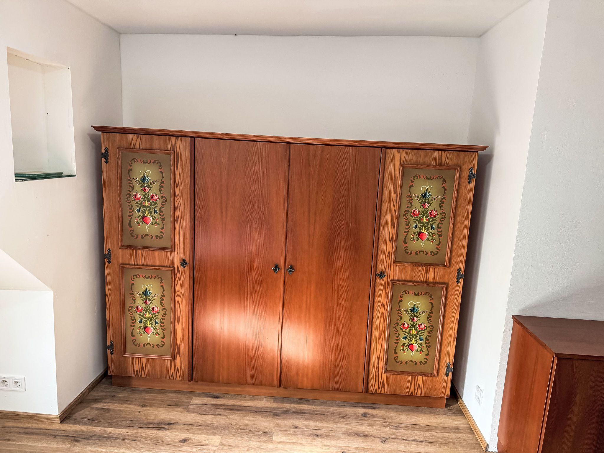 A wooden wardrobe with decorative glass panels and two handles.