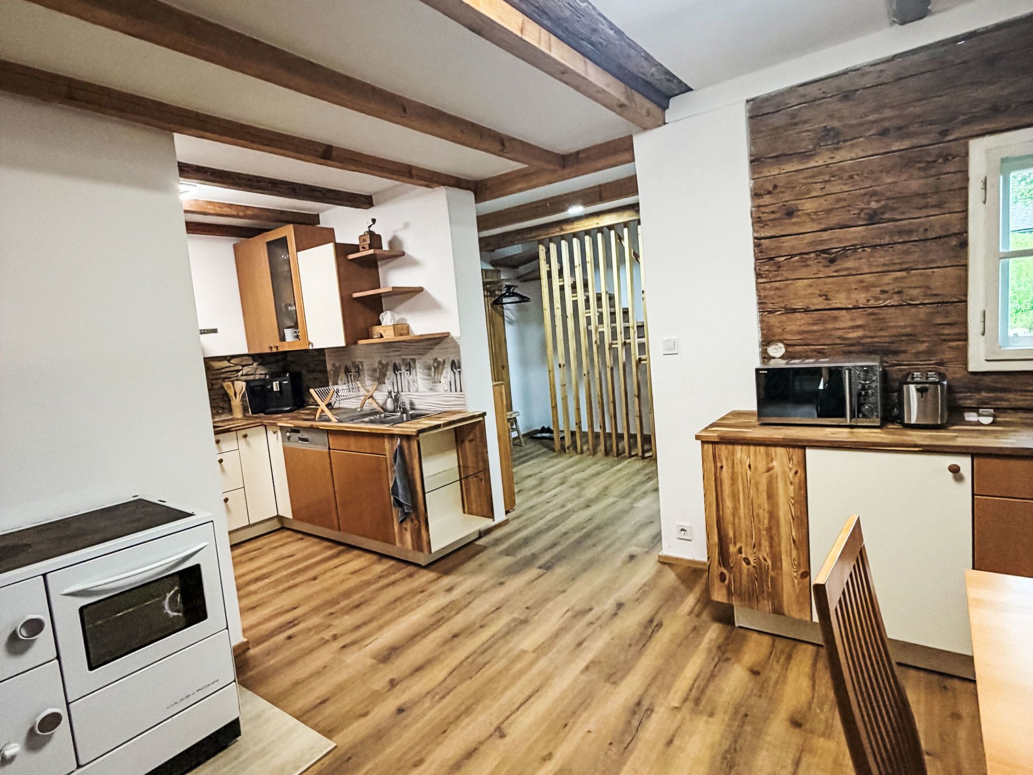Eine moderne Küche mit Holzboden, integrierten Geräten und einer Wand in Holzoptik.