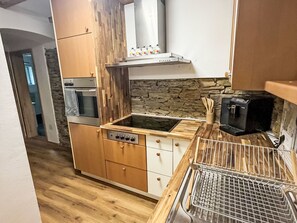 Una cocina funcional con armarios de madera, horno integrado, microondas y protector de encimera de piedra.