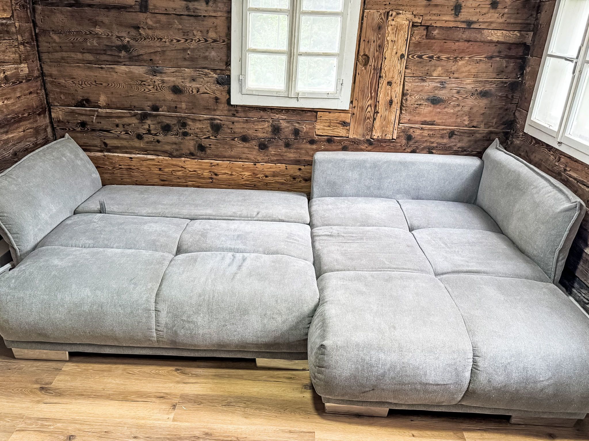 A wooden cabin interior with a sofa and a window.