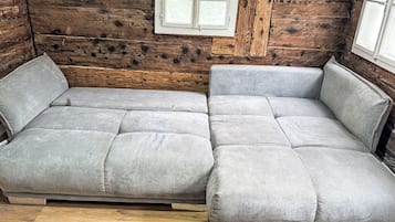 A wooden cabin interior with a sofa and a window.
