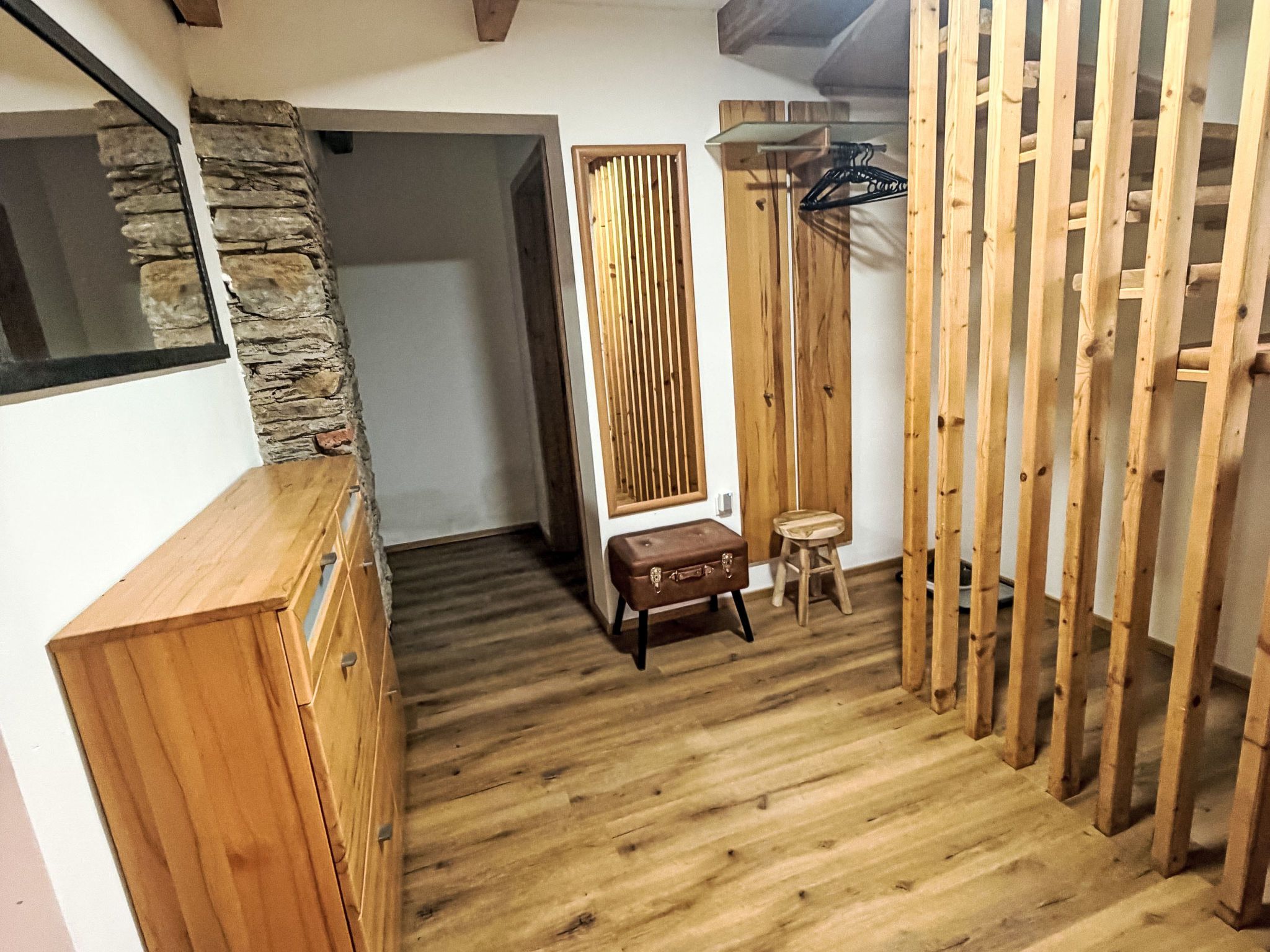 Ein Zimmer mit Holzboden, einer Wand aus Stein, einem Holzschrank, einer Bank und einer Holzwand.