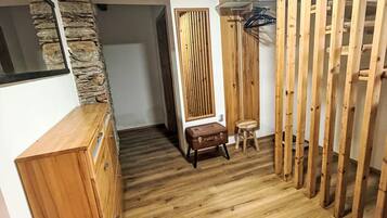 Ein Zimmer mit Holzboden, einer Wand aus Stein, einem Holzschrank, einer Bank und einer Holzwand.