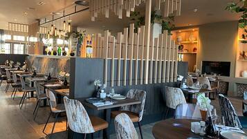 Een modern restaurant met houten inrichting, meerdere eettafels en stoelen.
