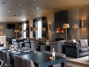 A modern living room with leather sofas, a coffee table, and wall-mounted lamps.