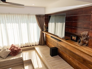 A modern living room with a sofa, a wooden entertainment unit, and a large mirror. - Tropical 4BD Villa, just 50 m from the beach. (Koh phangan)