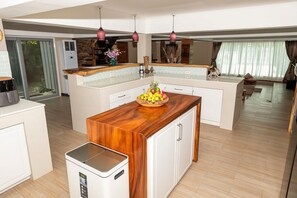 A modern kitchen with a central island, white cabinetry, and a wooden countertop. - Tropical 4BD Villa, just 50 m from the beach. (Koh phangan)