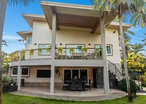 A two-story building with a balcony, outdoor seating, and a staircase. - Tropical 4BD Villa, just 50 m from the beach. (Koh phangan)