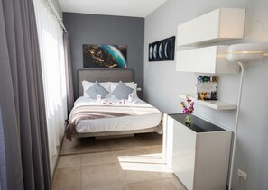 A modern bedroom with a bed, a desk, a lamp, and artwork on the walls. - Tropical 4BD Villa, just 50 m from the beach. (Koh phangan)