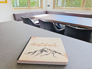 A book titled 'Gästebuch' on a table in a room with a view of trees through the windows. - "das maridl" by Interhome (Ried im Oberinntal)