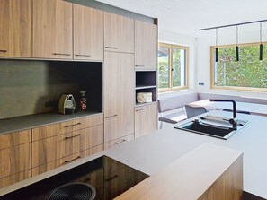 A modern kitchen with wooden cabinets, a built-in oven, and a window providing a view of greenery. - "das maridl" by Interhome (Ried im Oberinntal)