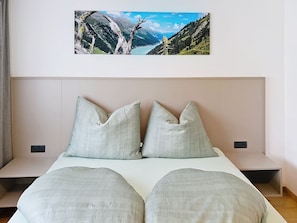 A bedroom with a bed, two pillows, a headboard, and a wall-mounted picture of a mountain landscape. - "das maridl" by Interhome (Ried im Oberinntal)