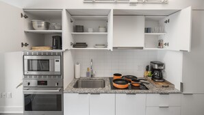 A modern kitchen with white cabinets, a built-in oven, a microwave, and a coffee maker. - StayToronto - Modern Bay Apartments (Toronto)