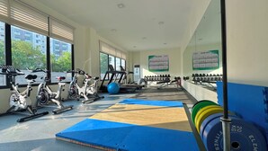 Une salle de sport équipée de matériel d’exercice, de tapis et d’un panneau affichant le règlement de la salle.
