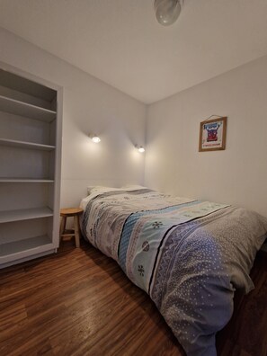 A bedroom with a bed, a wooden floor, a white wall, and a framed picture. - StFrançoisLongchamp - At the Base of the Slopes - Balcony, Elevator & Ski Locker—4–6 People (Saint François Longchamp)