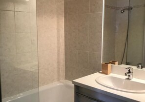 A bathroom with a bathtub, a sink, and a mirror. - StFrançoisLongchamp - At the Base of the Slopes - Balcony, Elevator & Ski Locker—4–6 People (Saint François Longchamp)