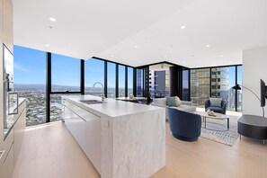 Un interior moderno con isla de cocina, zona de estar y grandes ventanales con vistas a la ciudad.