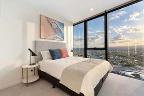 Ein Schlafzimmer mit großem Fenster, einem Bett, einem Nachttisch und einem Gemälde an der Wand.