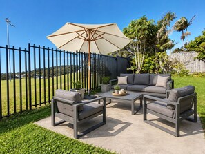An outdoor patio with a sectional sofa, two armchairs, a coffee table, and a large umbrella. - Sawtell Garden House Dog Friendly Huge Yard Sleeps 6 (Sawtell)