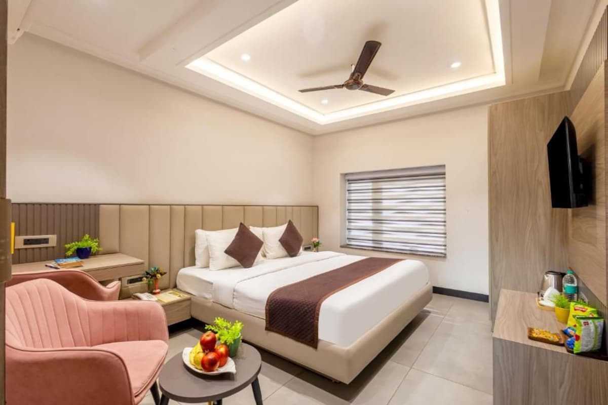 Ein modernes Hotelzimmer mit Bett, Schreibtisch, Stuhl, Fernseher und Deckenventilator.