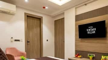 A hotel room with a bed, a ceiling fan, a television, and a small table with fruit.