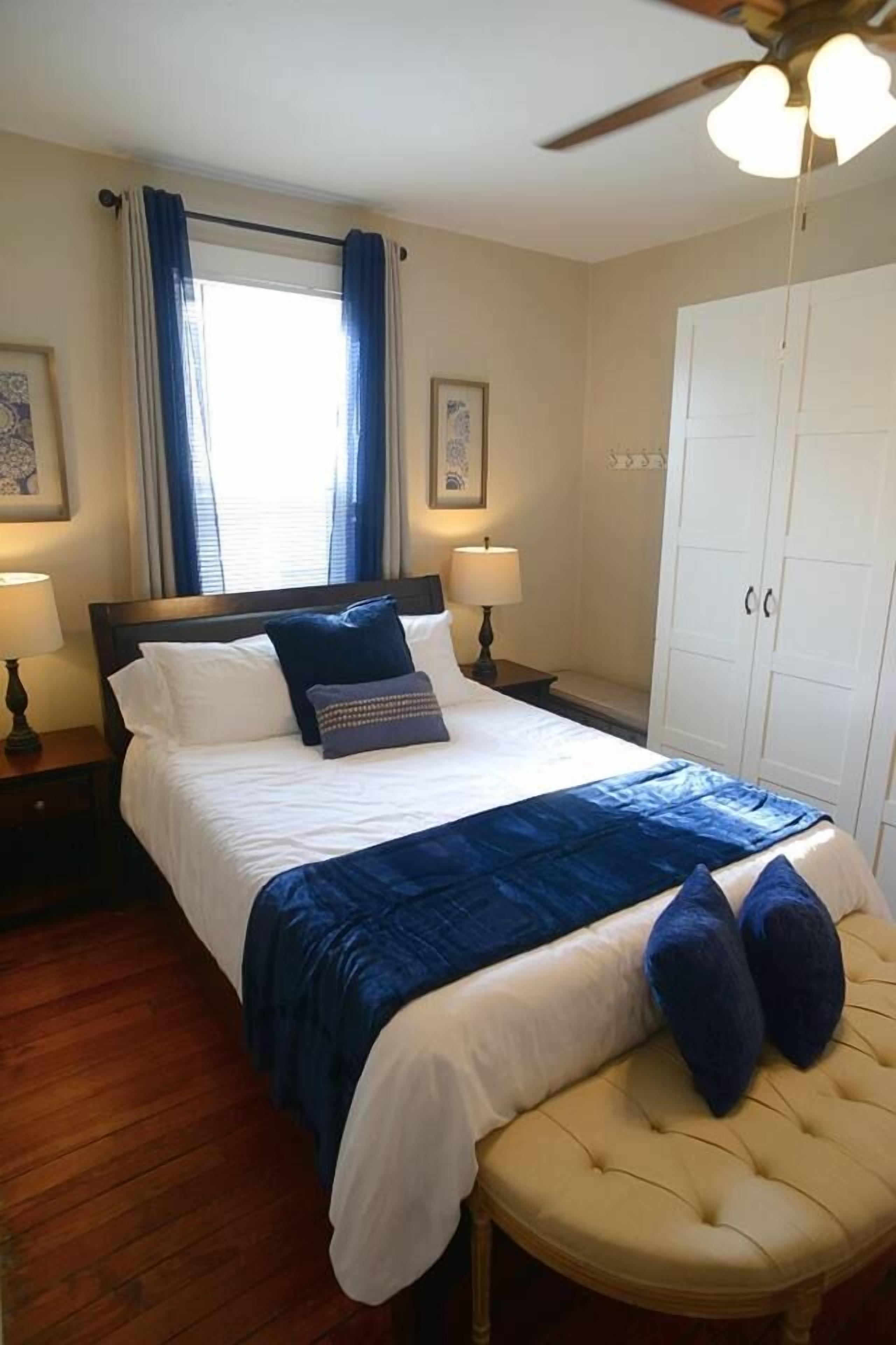 A hotel room with a bed, a nightstand, a wardrobe, and a ceiling fan.