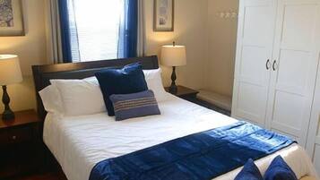 A hotel room with a bed, a nightstand, a wardrobe, and a ceiling fan.