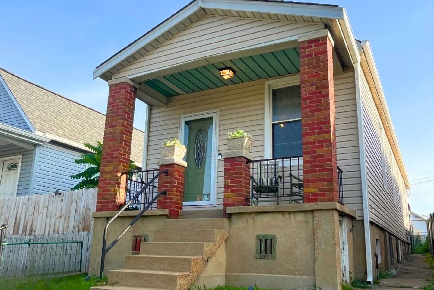 A two-story house with a front porch, a brick chimney, and a green awning.
