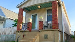 A two-story house with a front porch, a brick chimney, and a green awning. - The Hill District House - Kid Friendly, Walkable - Stay Smiley Rentals (St. Louis)